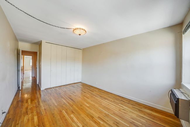 Unfurnished bedroom featuring light wood-style flooring, baseboards, a wall unit AC, and a closet | Image 10