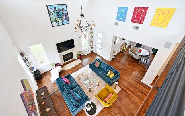 Living room featuring a towering ceiling, a chandelier, wood finished floors, and a glass covered fireplace | Image 7