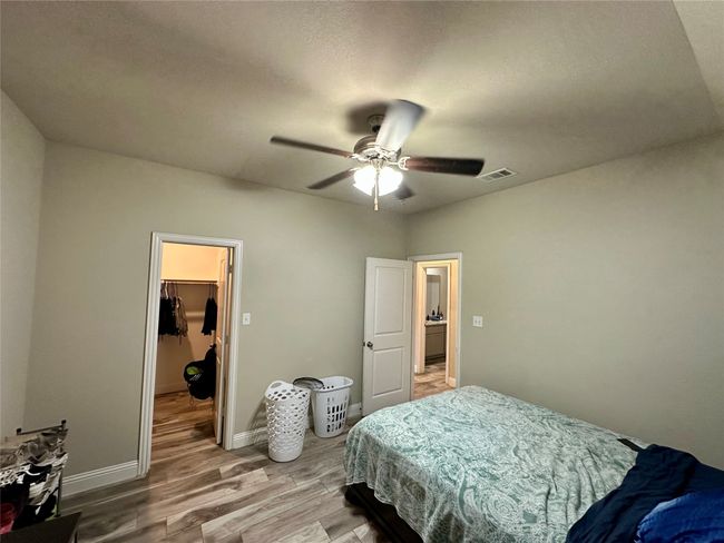 Bedroom featuring a walk in closet, light wood-style floors, ceiling fan, and a closet | Image 26