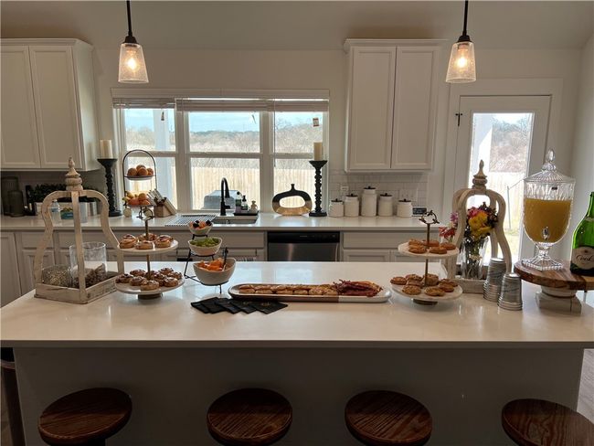 Kitchen with a breakfast bar, white cabinetry, and quartz countertops | Image 6