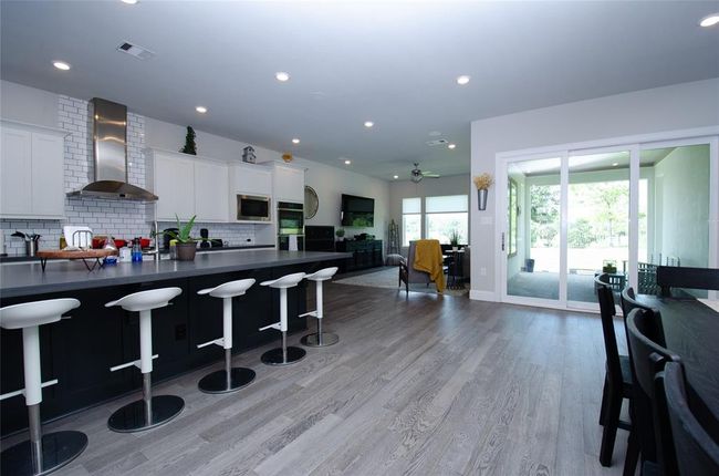 Dining and kitchen area with a three panel stacking slider door leading to the covered back patio. | Image 10