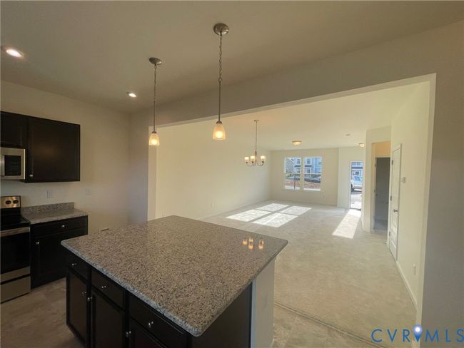 Kitchen with appliances with stainless steel finishes, open floor plan, a kitchen island, dark cabinetry, and recessed lighting | Image 9