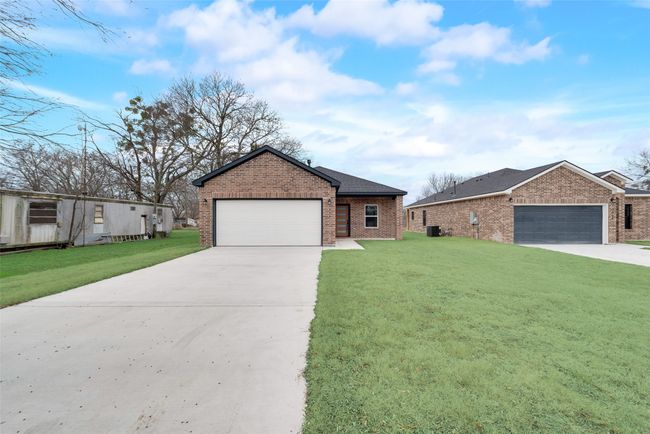 Ranch-style house featuring brick siding, driveway, a front lawn, and a garage | Image 28