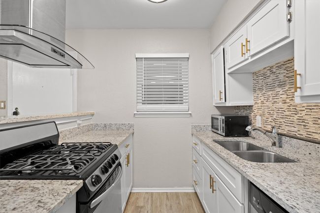 Granite countertop, venthood, tile backsplash, stainless appliances, stylish cabinet hardware. | Image 15
