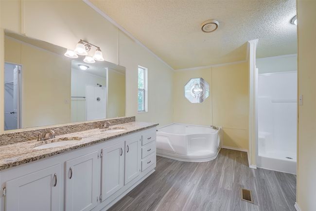 Bathroom with ornamental molding, a bath, wood finished floors, a stall shower, and double vanity | Image 20
