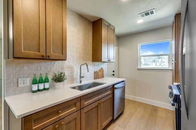 Kitchen featuring visible vents, decorative backsplash, appliances with stainless steel finishes, light wood-style floors, and a sink | Image 16