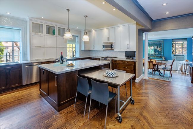 Kitchen featuring stainless steel appliances, white cabinets, a kitchen island, crown molding, and tasteful backsplash | Image 6