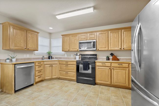 Kitchen featuring light tile patterned flooring, stainless steel appliances, light countertops, and light brown cabinetry | Image 15