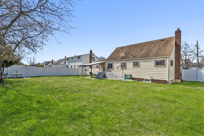 Back of house with a fenced backyard, a chimney, and a yard | Image 18