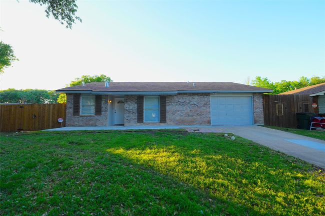 Single story home with brick siding, fence, a garage, a front lawn, and concrete driveway | Image 16