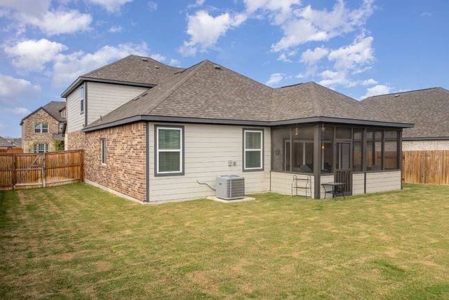 Back of house with central air condition unit, roof with shingles, a sunroom, and brick siding | Image 22