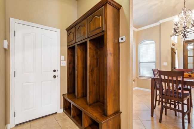 Mudroom with a chandelier, light tile patterned floors, crown molding, and baseboards | Image 33