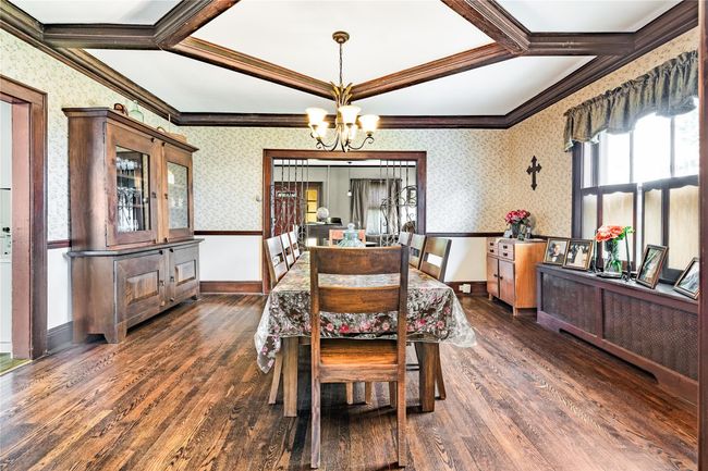 Dining area featuring wallpapered walls, wood finished floors, an inviting chandelier, and coffered ceiling | Image 14