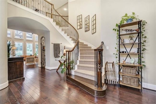 Elegant entryway features a grand curved staircase, rich engineered hardwood floors, and abundant natural light, creating a warm and inviting first impression. | Image 7