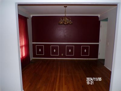 Empty room featuring dark hardwood / wood-style floors, crown molding, and a notable chandelier | Image 3