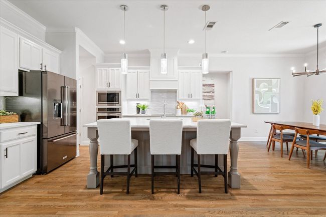 Kitchen featuring stainless steel appliances, crown molding, light countertops, tasteful backsplash, and white cabinetry | Image 10