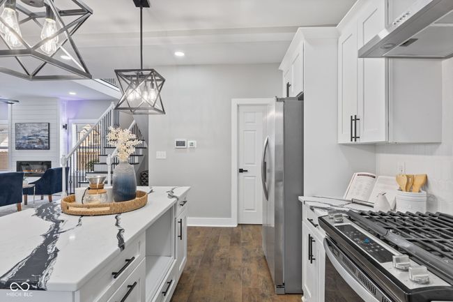 kitchen featuring recessed lighting, under cabinet range hood, a chandelier, appliances with stainless steel finishes, and a large fireplace | Image 11