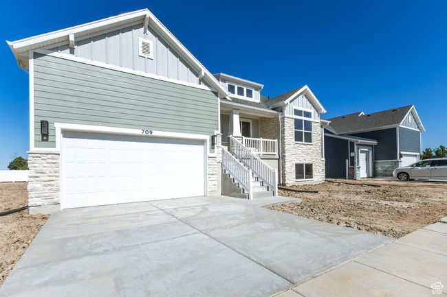 Craftsman-style home featuring stone siding, board and batten siding, driveway, and covered porch | Image 5