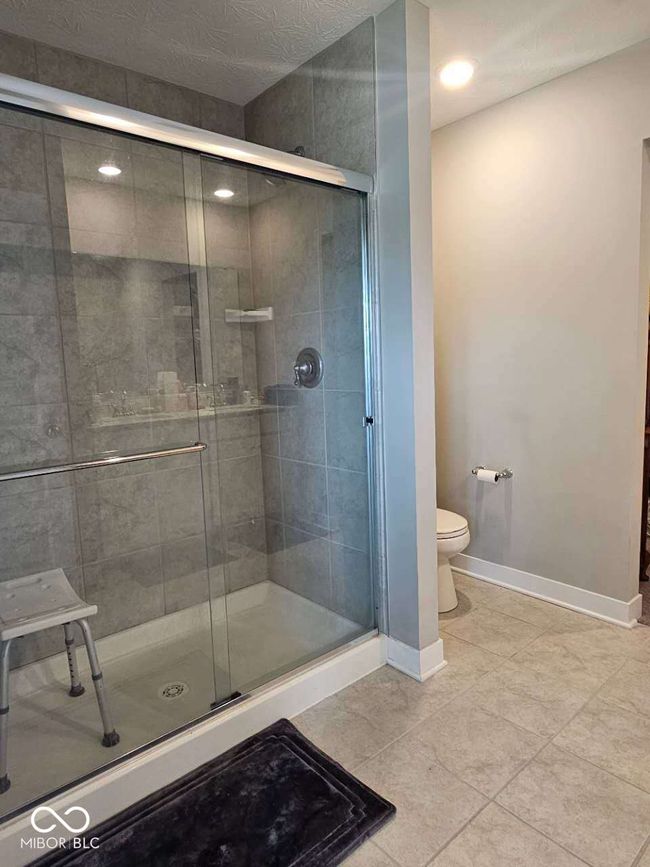 bathroom with toilet, baseboards, a stall shower, tile patterned floors, and recessed lighting | Image 22