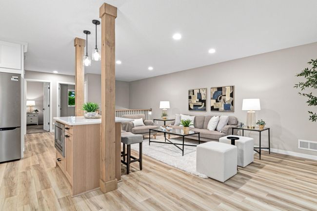 Stylish wood posts frame the island with pendant lighting above, while white quartz countertops and cabinetry offer a clean, fresh look. Built-in microwave and recycle center adds convenience. | Image 6