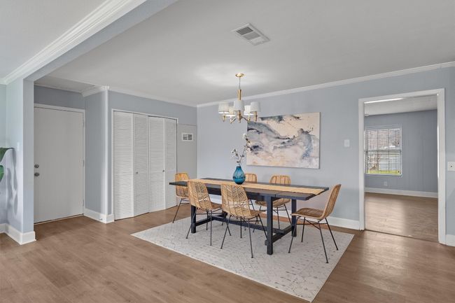 Dining space featuring wood finished floors, baseboards, visible vents, ornamental molding, and a notable chandelier | Image 10