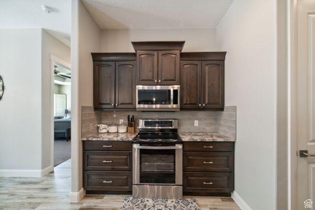 Kitchen featuring dark brown cabinetry, appliances with stainless steel finishes, and light stone countertops | Image 13