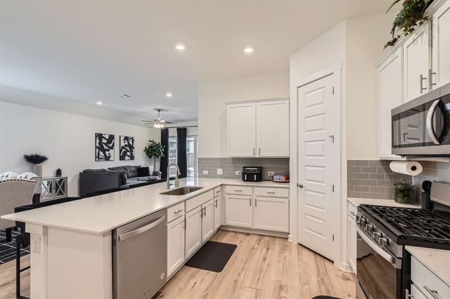 Kitchen with a sink, open floor plan, light wood-type flooring, a peninsula, and appliances with stainless steel finishes | Image 12