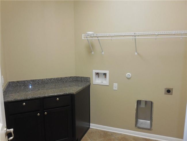 Washroom with washer hookup, electric dryer hookup, baseboards, cabinet space, and light tile patterned flooring | Image 12