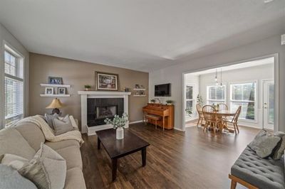 Living room with dark wood-type flooring, a tiled fireplace, and plenty of natural light | Image 3