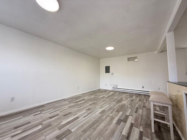 living room featuring electric panel, a baseboard heating unit, baseboards, and wood finished floors | Image 7