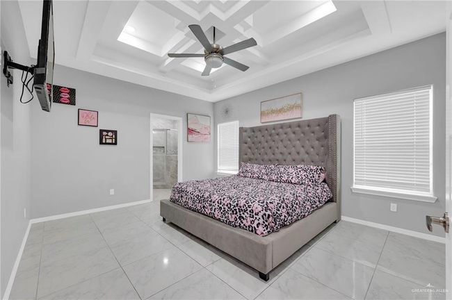 Bedroom with marble look tiles, ceiling fan, coffered ceiling, ensuite bath, and beam ceiling | Image 16