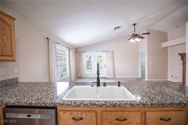 Kitchen featuring a sink, visible vents, vaulted ceiling, dark countertops, and dishwasher | Image 10