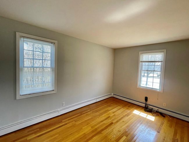 Spare room featuring wood finished floors and a baseboard heating unit | Image 17