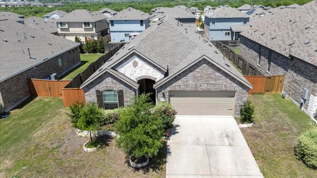 View of front of home featuring driveway, stone siding, fence, a garage, and a residential view | Image 5
