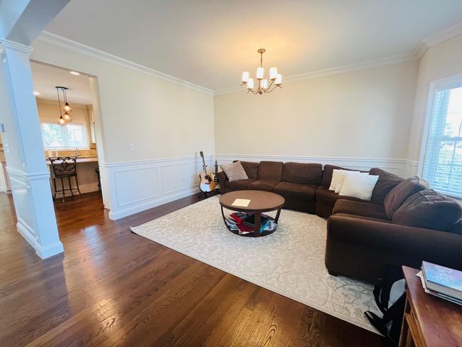 Living area featuring a chandelier, ornate columns, dark wood-style flooring, ornamental molding, and a wainscoted wall | Image 9