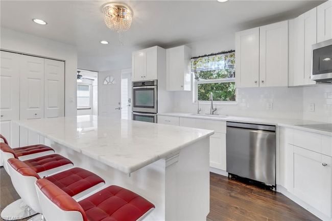 Another view of the updated kitchen! Gorgeous marble counter tops, spacious island, sleek tile backsplash, double oven, large pantry, oversized sink that looks out to the backyard! | Image 8