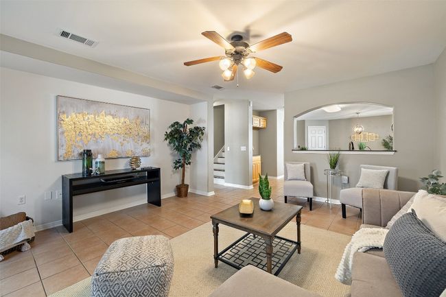 Living area featuring light tile patterned floors, stairway, ceiling fan, arched walkways, and baseboards | Image 16