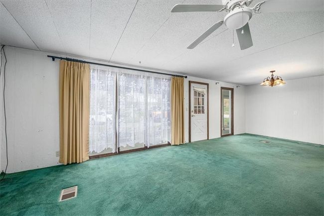 Empty room with wooden walls, carpet floors, visible vents, and ceiling fan | Image 14