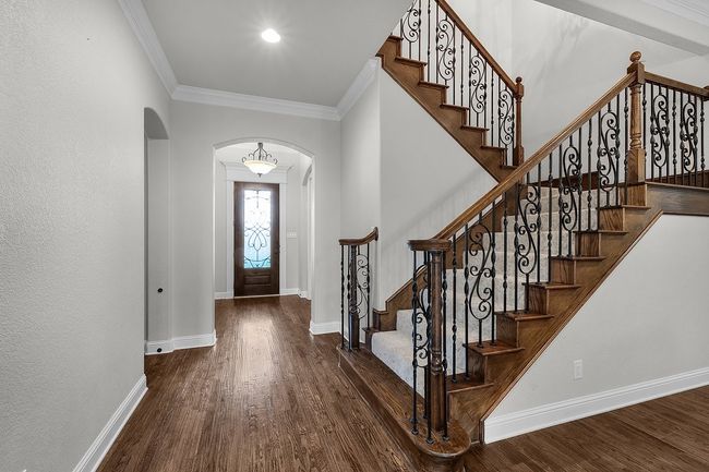 Foyer with arched walkways, wood finished floors, baseboards, crown molding, and stairs | Image 4
