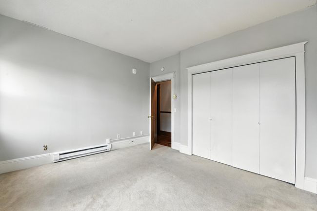 Bright and airy bedroom with soft neutral walls, baseboard heat, and a spacious double-door closet. | Image 21