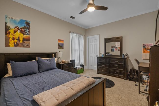 Bedroom featuring light colored carpet, ornamental molding, a ceiling fan, and a desk | Image 31