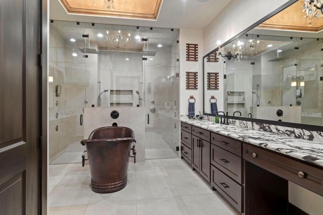 Primary bath accenting 1 of 2 vanity areas, copper soaking tub and massive walk-in shower with multiple rain and body shower heads. | Image 29