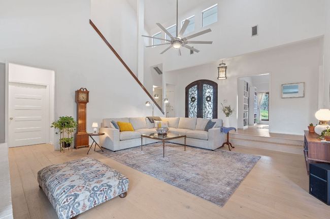 Living room with a high ceiling, wood finished floors, and a ceiling fan | Image 4