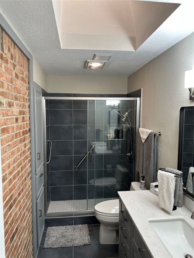 Full bath with toilet, a textured ceiling, a shower stall, tile patterned flooring, and vanity | Image 14