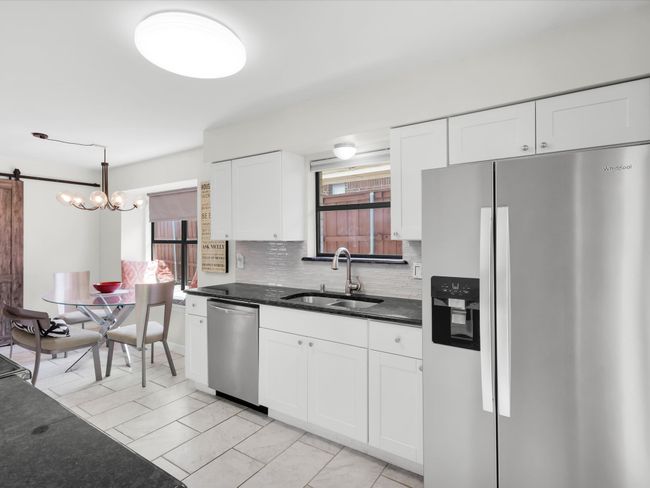 Kitchen with stainless steel appliances, white cabinetry, backsplash, and pendant lighting | Image 5