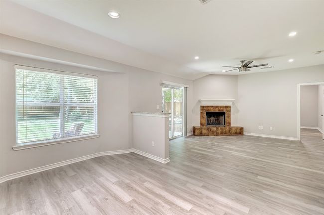 Kitchen eating area with living room with ceiling fan, light wood-style flooring, recessed lighting, a fireplace, and lofted ceiling | Image 8