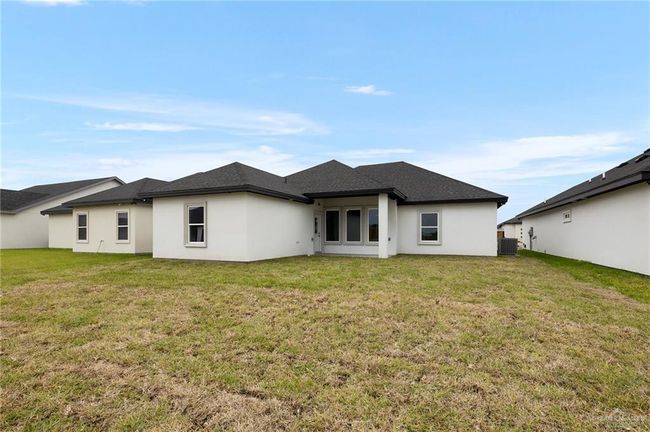 Rear view of property with central AC, stucco siding, and a lawn | Image 14