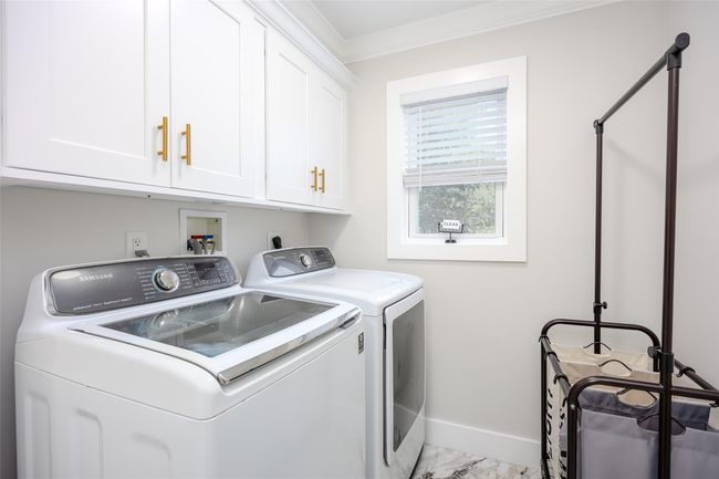 Washroom featuring washing machine and clothes dryer, ornamental molding, marble look tiles, and cabinet space | Image 15
