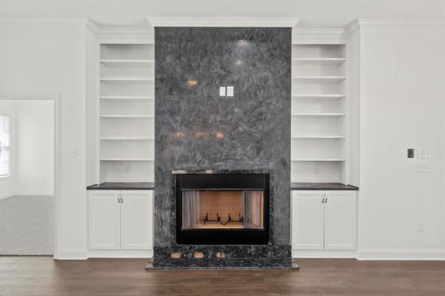 Detailed view of a fireplace, built in features, wood finished floors, and ornamental molding | Image 6