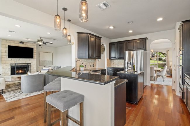 Kitchen featuring pendant lighting, a center island, a kitchen breakfast bar, open floor plan, and arched walkways | Image 15